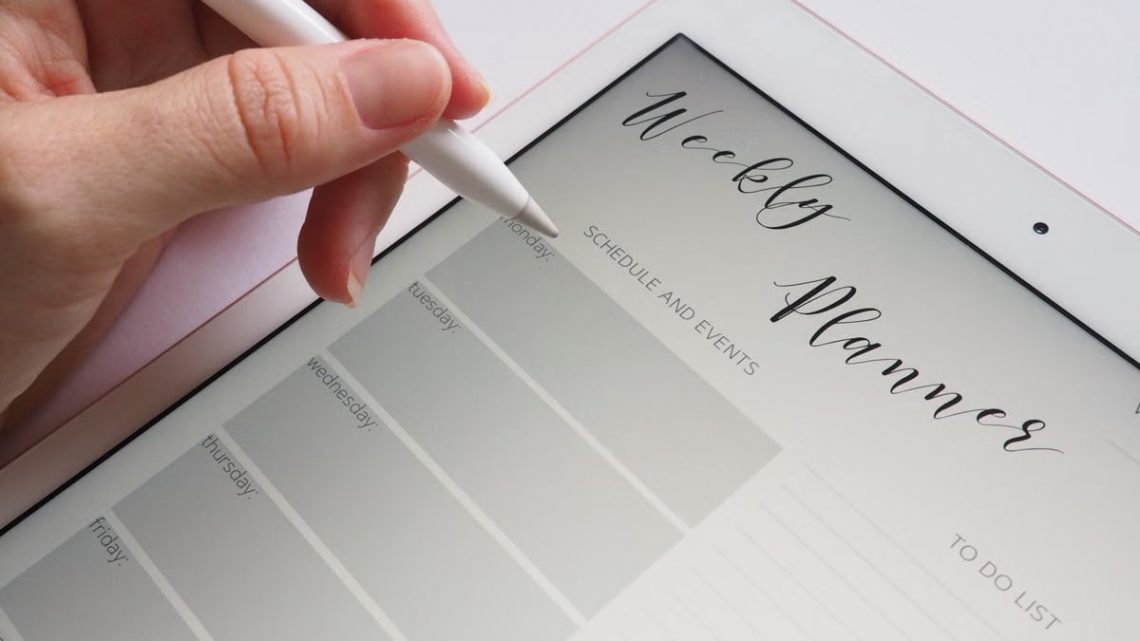 A stylus writing in a digital weekly planner on a tablet screen, ideal for organization.