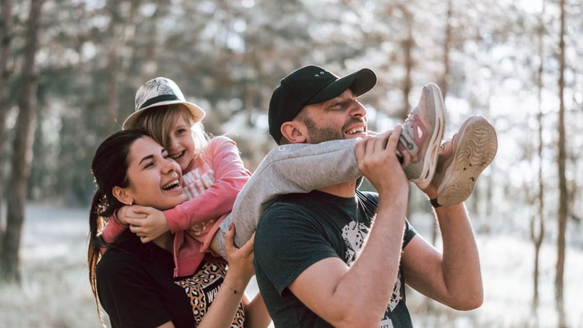Happy family having fun in a forest, capturing joyful bonding moments.